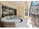 Covered patio featuring a wicker circular couch and view of the screened-in pool area at 2710 Manesty Ln, Kissimmee, FL 34747