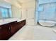 Well-lit bathroom featuring double sink vanity, soaking tub, mosaic wall accents, and marble flooring at 7443 Lake Albert Dr, Windermere, FL 34786