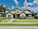 Beautiful two-story home with a manicured lawn, stone accents, and a tile roof under a sunny sky at 7443 Lake Albert Dr, Windermere, FL 34786