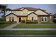 Charming two-story home featuring a well-maintained lawn, stone accents, and warm exterior lighting at dusk at 7443 Lake Albert Dr, Windermere, FL 34786