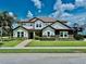 Beautiful two-story home featuring a well-manicured lawn, decorative stone accents, and lush landscaping at 7443 Lake Albert Dr, Windermere, FL 34786