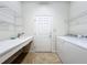 Clean laundry room with built-in sink, storage shelves, and appliances near the entry door at 9582 Sw 70Th Loop, Ocala, FL 34481