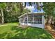 Exterior view of the screened-in porch and spacious backyard with lush green grass and mature trees at 3610 Pershing Ave, Orlando, FL 32812