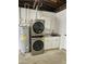 Laundry area inside of the garage featuring a stacked washer/dryer, sink, and water heater at 3610 Pershing Ave, Orlando, FL 32812