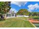 Manicured lawn leading to a patio, dock, and waterfront with mature trees and landscaping at 5810 Lake Victoria Dr, Lakeland, FL 33813