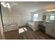 Well-lit bathroom features a tub, vanity with granite countertop, and wood-look floors at 1142 Blarney St, Minneola, FL 34715