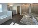 Bright bathroom boasts dual sinks, soaking tub, walk-in shower, and wood flooring at 1142 Blarney St, Minneola, FL 34715