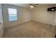 This bedroom features neutral carpet, a ceiling fan, a window with blinds, and a mounted television at 1142 Blarney St, Minneola, FL 34715