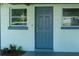 Classic blue front door framed by white siding and matching trimmed windows at 1501 7Th Se St, Winter Haven, FL 33880