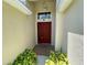 Close-up shot of a welcoming front entryway with a red door and neatly trimmed green bushes at 1003 Clearpointe Way, Lakeland, FL 33813
