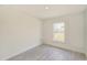 Clean, minimalist bedroom with neutral walls, a window for natural light, and stylish wood-look flooring at 1204 Alafia Way, Kissimmee, FL 34759