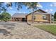 Brick home exterior featuring a metal roof, covered porch with swing, and a circular brick driveway at 6820 County Road 561, Clermont, FL 34714