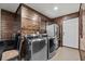 Rustic laundry room featuring a front load washer, dryer, stainless refrigerator, and natural wood paneling at 6820 County Road 561, Clermont, FL 34714