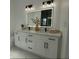 Bright bathroom featuring a double vanity with an LED backlit mirror and modern black hardware at 8456 Se 164Th Pl, Summerfield, FL 34491