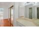 Bright bathroom with large mirrors, vanity, closet, and wood floors leading to a tub at 1125 English Garden Ln, Winter Garden, FL 34787
