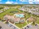 Aerial view of a community pool with a clubhouse, playground, tennis court, and parking lot at 11865 Ginsberg Pl, Orlando, FL 32832