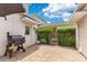 Private backyard with a brick patio, grill, lush greenery, and a cozy outdoor dining space at 11865 Ginsberg Pl, Orlando, FL 32832