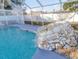 Screened-in pool featuring a rock waterfall feature for ultimate relaxation and enjoyment at 3955 Sw 139Th Street Rd, Ocala, FL 34473