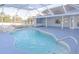 Beautiful inground pool in screened-in lanai with rock waterfall and outdoor kitchen area at 3955 Sw 139Th Street Rd, Ocala, FL 34473