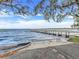 View of the lake with a wooden dock, concrete boat ramp, and mature trees adding to the natural beauty at 9632 Spring Lake Dr, Clermont, FL 34711