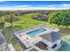 Aerial view of a fenced community pool area with lounge chairs, tables, and a nearby tennis court at 9632 Spring Lake Dr, Clermont, FL 34711