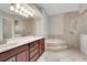 Luxurious bathroom featuring double sinks, a large mirror, and a soaking tub with tile surround at 508 Bacio St, New Smyrna Beach, FL 32168