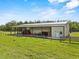 Side view of the home's outbuilding, including a barn and equipment storage area on a fenced lot at 11657 Moore Rd, Lakeland, FL 33809