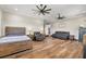 Main bedroom featuring wood floors, ceiling fans, a king bed and leather sofas at 11657 Moore Rd, Lakeland, FL 33809