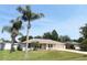Inviting single-Gathering home featuring a lush green lawn, palm trees, and a paved driveway leading to an attached garage at 2521 Tamarind Dr, Edgewater, FL 32141