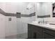 Modern bathroom featuring a glass enclosed shower with unique tile accents and a gray vanity with marble countertop at 1514 Corolla Ct, Reunion, FL 34747