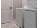 Functional laundry room with white washer and dryer, complemented by neutral wall paint and modern tile floor at 1514 Corolla Ct, Reunion, FL 34747