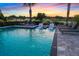 Sparkling pool with fountains, sun loungers, and a picturesque golf course view at sunset at 1514 Corolla Ct, Reunion, FL 34747