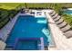Aerial view of a luxury pool with spa, sun loungers, and an outdoor seating area at 1514 Corolla Ct, Reunion, FL 34747