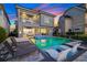 Backyard pool area featuring modern lounge chairs and an illuminated pool, perfect for nighttime relaxation at 1514 Corolla Ct, Reunion, FL 34747