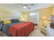 Well-lit bedroom with neutral walls, featuring a ceiling fan, a large bed and dresser with lamps at 2382 Due West Dr, The Villages, FL 32162