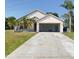 Exterior of home with attached garage, concrete driveway, and lawn at 323 Miami Ln, Kissimmee, FL 34759