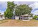 View of the backyard showing the back of house, large trees and a dilapidated carport structure at 515 New York Ave, St Cloud, FL 34769