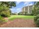 Lush green space with palm trees surrounds a modern building complex under a bright blue sky at 4 Oceans West Blvd # 502B, Daytona Beach, FL 32118