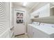 Bright laundry room features white washer and dryer, upper cabinets, and access to the exterior at 8166 Sw 80Th Ter, Ocala, FL 34476