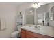 Bright bathroom featuring a white vanity, built-in shelving, toilet, and a large mirror reflecting the bedroom at 1787 Foliage Ln, The Villages, FL 32162