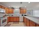 Bright kitchen featuring wood cabinets, white appliances, tile flooring, and ample countertop space at 1787 Foliage Ln, The Villages, FL 32162