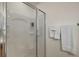 Close up of a clean shower with glass doors and towels hanging nearby at 1787 Foliage Ln, The Villages, FL 32162
