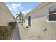 A view of the side yard with concrete walkway and exterior wall at 1787 Foliage Ln, The Villages, FL 32162