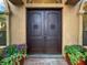 Elegant front entryway featuring double doors, stucco surround, decorative sidelights, and potted flowers at 6567 Eagle Ridge Way, Lakeland, FL 33813