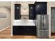 Elegant butler's pantry featuring black cabinetry, marble countertops, and stainless steel refrigerator at 6567 Eagle Ridge Way, Lakeland, FL 33813