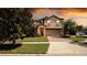 Charming two-story home featuring manicured landscaping and a brick-paved driveway leading to a two-car garage at 1450 Rolling Fairway Dr, Davenport, FL 33896