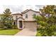 Charming two-story home featuring manicured landscaping and a brick-paved driveway leading to a two-car garage at 1450 Rolling Fairway Dr, Davenport, FL 33896