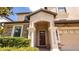 Inviting front porch with stone accents, stately columns, and a beautiful wood front door at 1450 Rolling Fairway Dr, Davenport, FL 33896