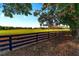Picturesque backyard with a wooden fence, sprawling green fields, and mature trees under a blue sky at 2899 Sw 66 St, Ocala, FL 34476