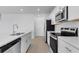 Modern white kitchen showcasing stainless steel appliances and quartz countertops, perfect for culinary enthusiasts at 5133 Forget Me Not Ave, Lake Hamilton, FL 33851